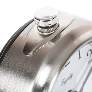 Close-up of a brushed silver metal clock body with a polished silver crown and a white clock face showing black numerals.