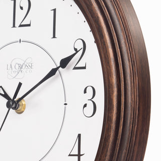 Close-up view of the frame of the 404-2630W Evelyn analog wall clock features a bronze finish frame and stylized black numbers on a white dial.