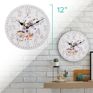 Dimension image in split screen showing the 404-2631T 12-inch Teatime Wall Clock head-on and in a lifestyle setting. The clock measures 12 inches in diameter and features an image of a floral teapot and teacup on a light-textured background, with the text "Tea Time," white numbers, black metal hands, and an open face design.
