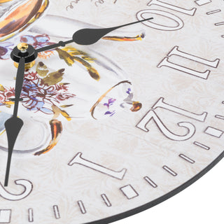 Top-down detail image of the 404-2631T 12-inch Teatime Wall Clock. The clock features an image of a floral teapot and teacup on a light-textured background, with the text "Tea Time," white numbers, black metal hands, and an open face design.