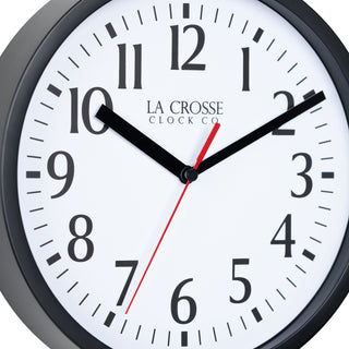 Close-up image of the 404-3020B 8-inch Basics Analog Wall Clock – Black dial. The clock features a black flush-mount frame, a white dial with black numbers, black hour and minute hands, and a red second hand.