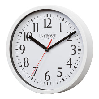 Left-facing image of the 404-3020W 8-inch Basics Analog Wall Clock – White. The clock features a white flush-mount frame, a white dial with black numbers, black hour and minute hands, and a red second hand.