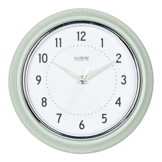 Head-on image of the 404-3024PH 9.5-inch Diner Wall Clock - Pistachio. The clock features an off-white dial with black numbers, pistachio hour dots, pistachio hour and minute hands, and a silver accent second hand set within a vintage-retro pistachio green frame.