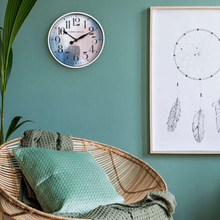 404-3028A 10.8-inch Brushstroke Wall Clock hanging on a green wall with a rattan papasan chair, dream catcher wall art print and a plant