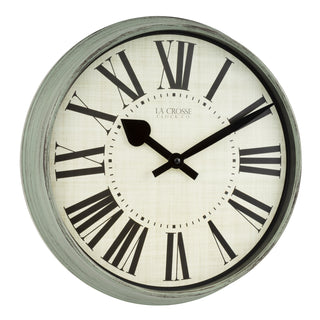 A round wall clock with a distressed gray-green painted frame, black Roman numerals, and black hands on a textured off-white face. The brand name 'LA CROSSE CLOCK CO.