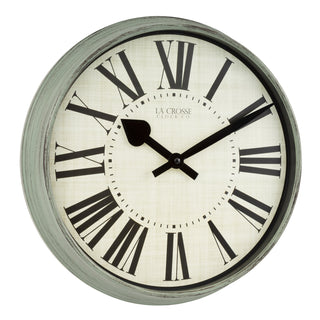 Right-facing image of the 404-3036G 14-inch Sagebrook Wall Clock featuring a sage green distressed decorative frame, an ivory linen design dial, bold black Roman numerals, and decorative black metal hour and minute hands. The brand name 'LA CROSSE CLOCK CO.' appears under the number 12 in the center of the clock.