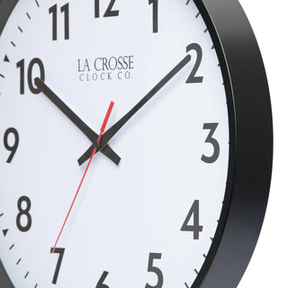Closeup view of a the frame and the dial of a white wall clock with black numbers, red second hand, showing the time as 10:10.