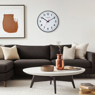 Transitional style living room with a 19-inch commercial clock from La Crosse Clock Co., abstract art on the wall, dark gray sofa, and a white with black legs coffee table.
