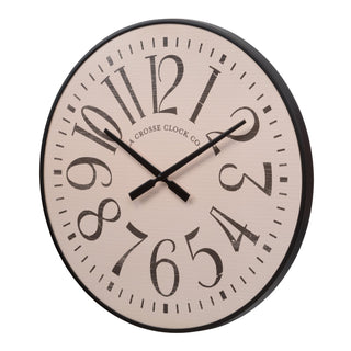 A round wall clock with a light beige face, black frame, and oversized black Arabic numerals. The brand name 'A CROSSE CLOCK CO.