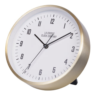 404-3715B A round analog desk clock with a brushed gold metal frame, a white dial, black Arabic numerals, and black hands. The brand name 'LA CROSSE CLOCK COMPANY' is printed on the face.