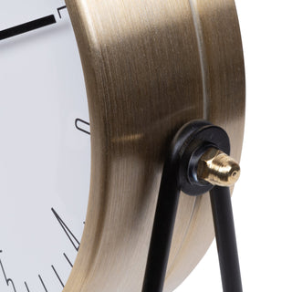 404-3719 Close-up of a modern table clock showing a brushed brass/gold-toned curved frame, black tripod legs, and a white clock face with black minimalist numerals.