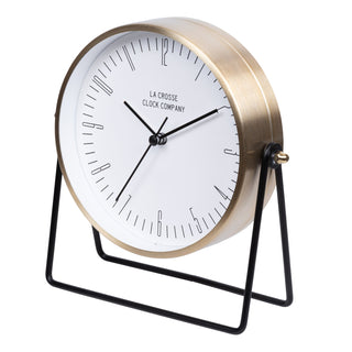 404-3719 A modern tabletop clock with a brushed gold metal cylindrical body, a white dial, black hands, and a black wire stand. The brand name 'LA CROSSE CLOCK COMPANY' is printed on the dial.