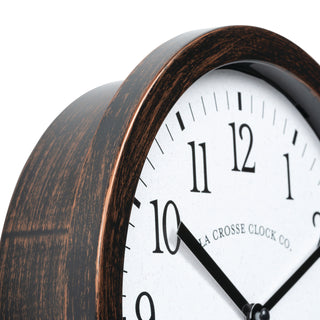 404-3825HC Close-up of a wall clock showing a dark brown wood-grain frame and a white face with black numerals and hands. The brand name 'Crosse Clock Co.