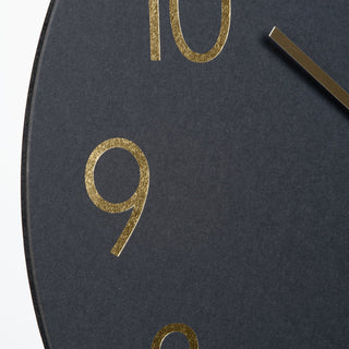 Black clock face with gold numbers and hands on a white background