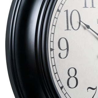 Close-up of a round wall clock showing a black ribbed frame and part of a white face with black Arabic numerals and clock hands.