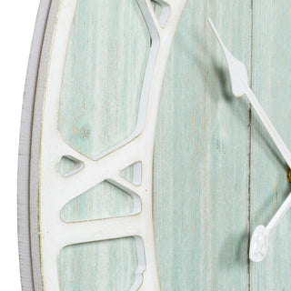 Close-up detail of the layered construction in wood of the 404-4060 23.5‑inch Harbor Tides wall clock features a distressed light teal wooden frame with an open face dial design, wood cut out Roman numerals in a light distressed white, and decorative metal hour and minute hands.