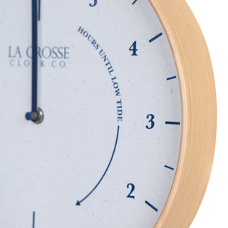 Close-up image of the natural wood frame detail of the 425-3831 11.8-inch Tide Wall Clock. The clock features a light wood frame, a white and tan speckled dial, blue numbers, markings, and a blue metal hand.