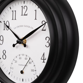 Close-up image of the frame of the 433-3020B 8-inch Colby Indoor/Outdoor Wall Clock with temperature featuring a dark decorative frame, a white dial with black numbers, a Fahrenheit temperature gauge, and black metal hands.