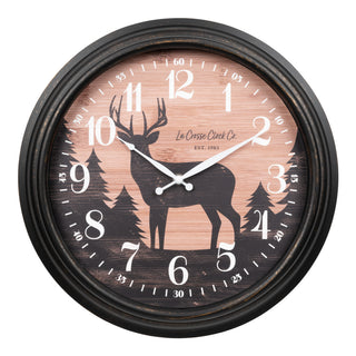 433-3841D A round wall clock with a distressed black frame, featuring a rustic wood-grain dial with a black deer silhouette, pine trees, and white numerals. The brand name 'La Crosse Clock Co' is printed on the dial.