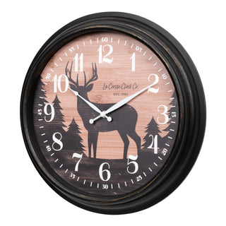 433-3841D A round wall clock with a distressed black frame and a rustic wood-grain face featuring a black deer silhouette, pine trees, and white numerals. The brand name 'La Crosse Clock Co' is printed on the clock face.