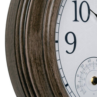 Close-up of a round wall clock showing a layered wood-grain frame in dark brown tones, a white clock face with black numerals, and a small gold-toned center detail.