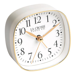 A white square alarm clock with gold accents and black numbers.